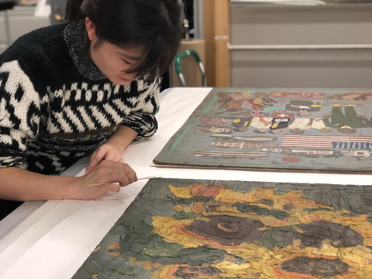 A conservator working on a painting