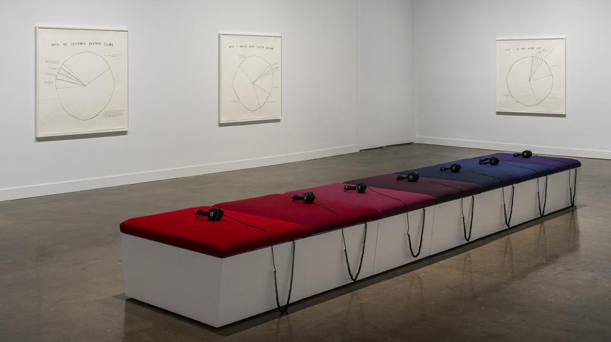 A photograph of a gallery with headphones on colorful benches