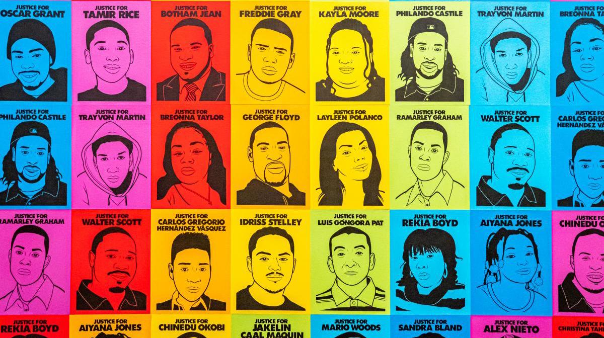 An installation photograph of an artwork of faces in a rainbow tone