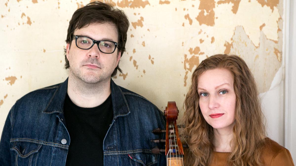A photograph of a woman and a man against a wall.