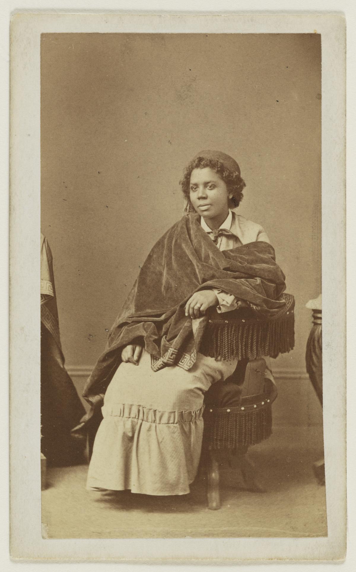 An African American woman sitting in a chair wearing a shawl