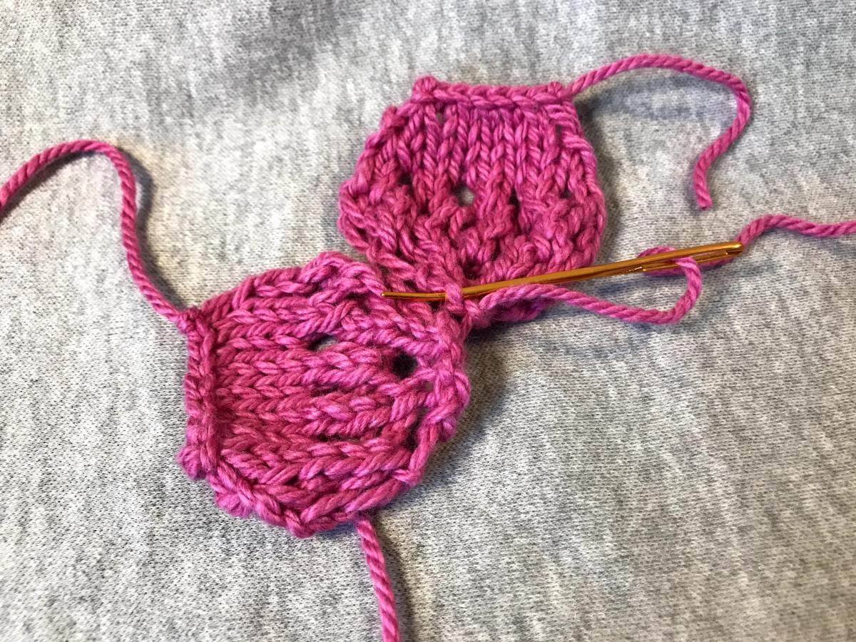 Two pink knitted cherry blossom petals joined for flower