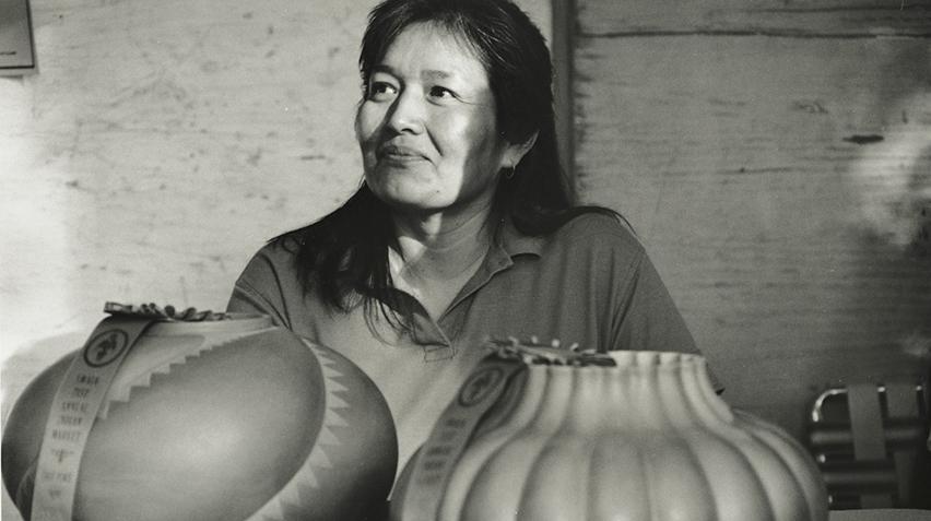 Blog_Christine McHorse_April 2021_sized for homepage A black and white photograph of a woman sitting behind two ceramic pots