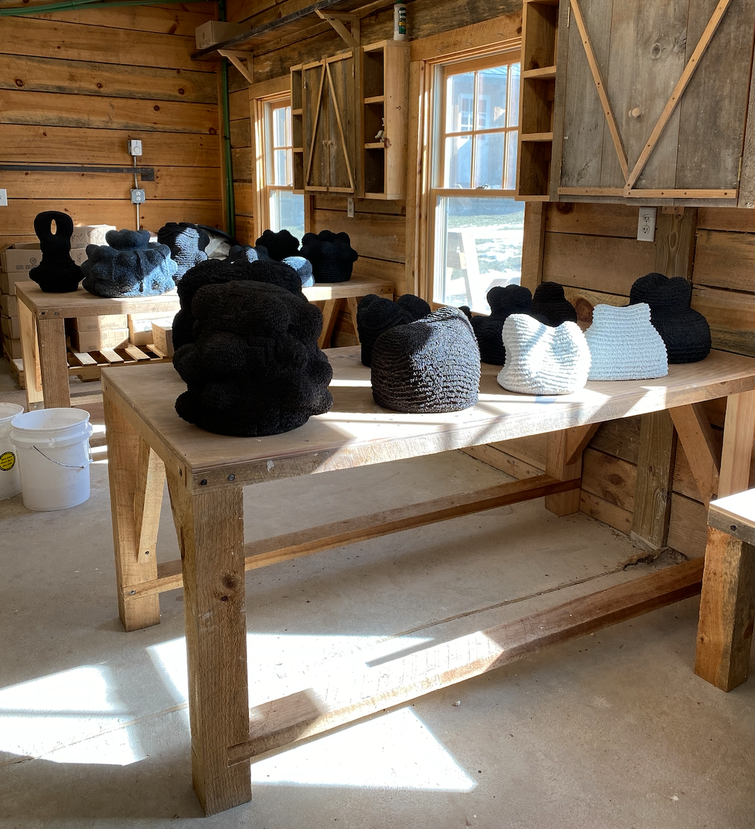 Interior of artist studio with several sculptures on rough wooden tables
