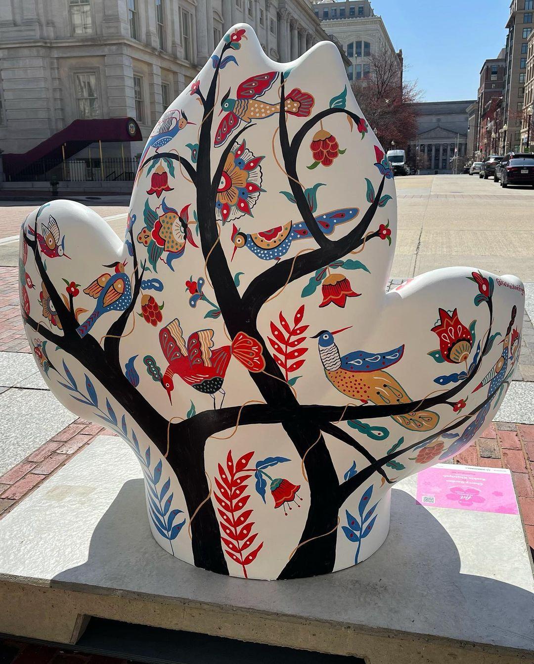Back view of cherry blossom sculpture with trees and birds.