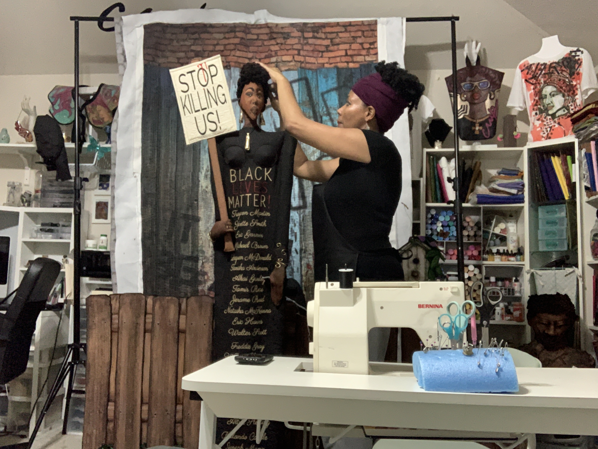 The artist standing near her sewing machine working on a Black Lives Matter artwork