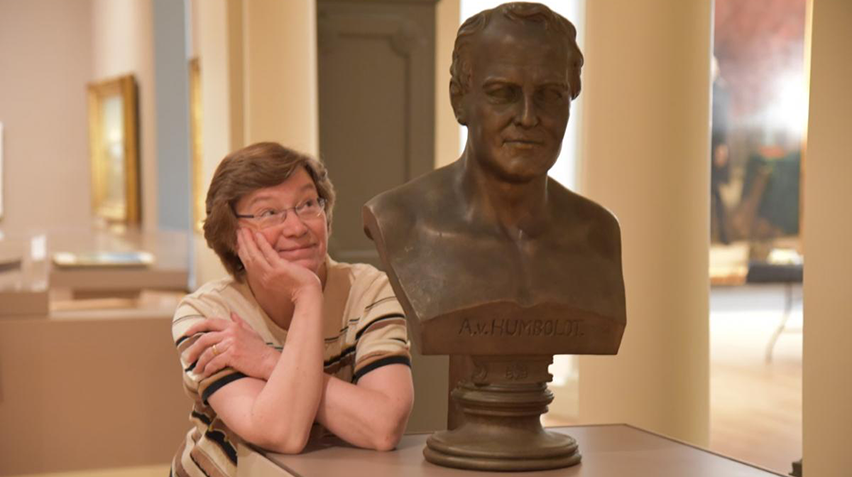 A woman looks up at a bust.