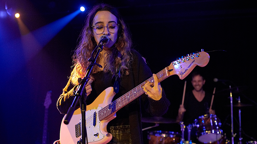Rachel Kline, of the band Flowerbomb, plays a guitar on a stage