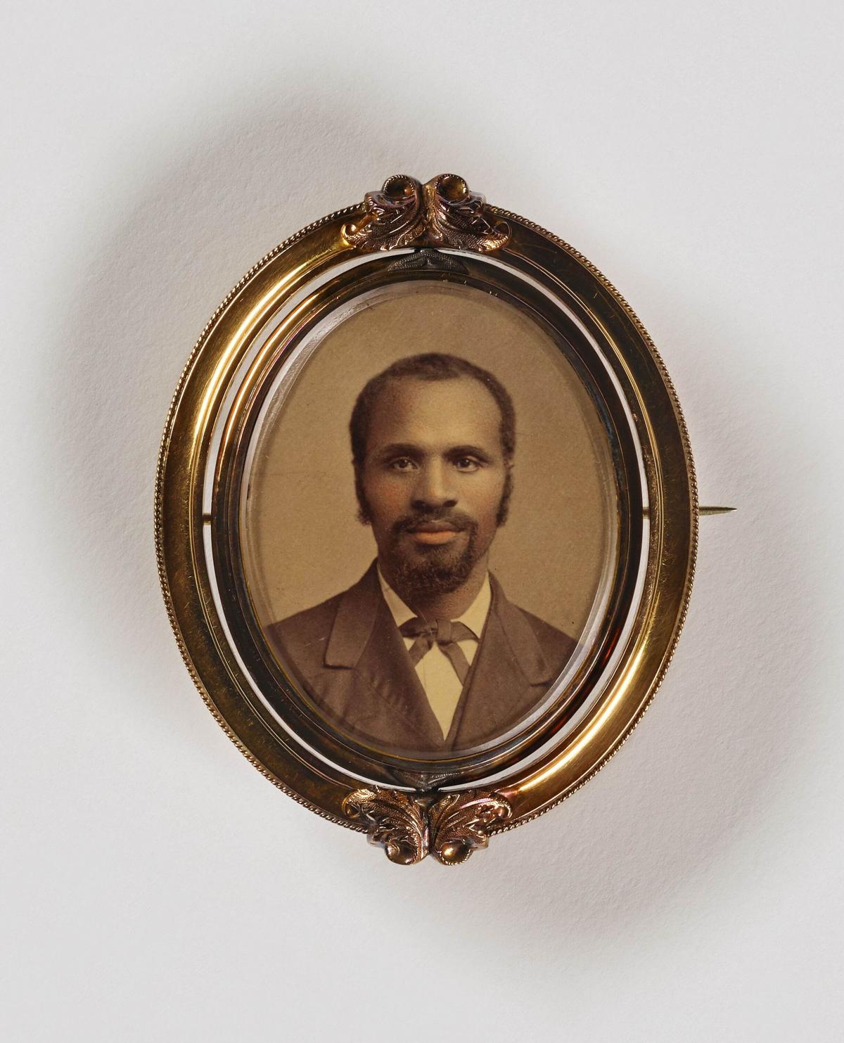 A gilded frame houses a photograph of a man with a goatee