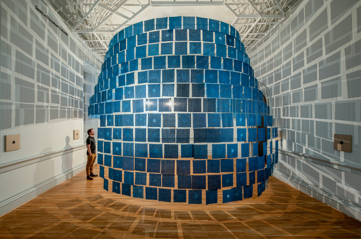 An installation view of small indigo cloths hanging from the ceiling