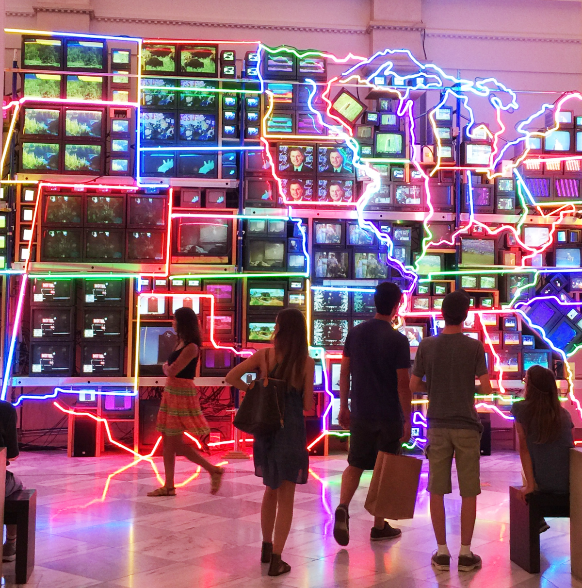 Visitors viewing "Electronic Superhighway" installation, made up of video monitors and neon lights.