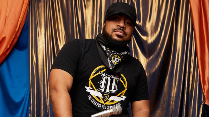 Eemcee Night Train 357 poses with his WAMMIE trophy in front of a gold curtain.
