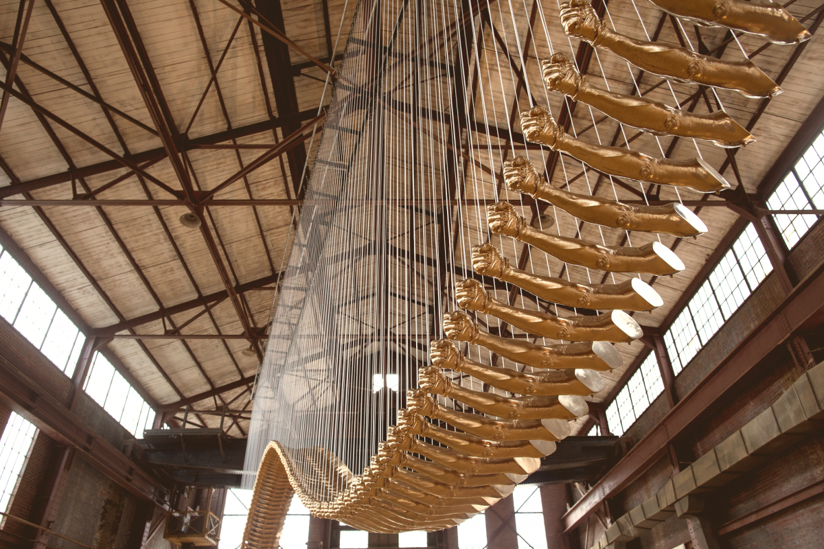 A sculpture of fiberglass fists painted gold, connected like a bridge