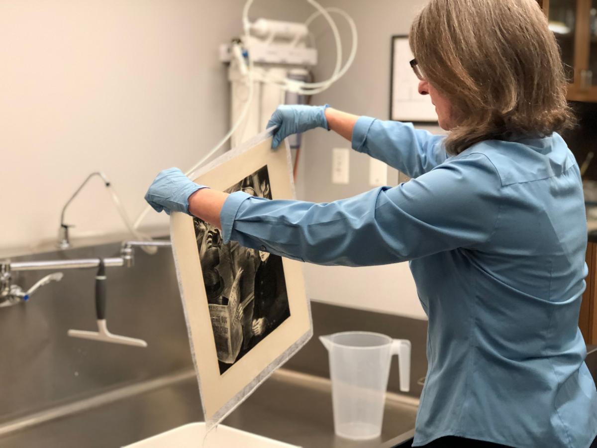 Conservator pulling a print from the sink of water