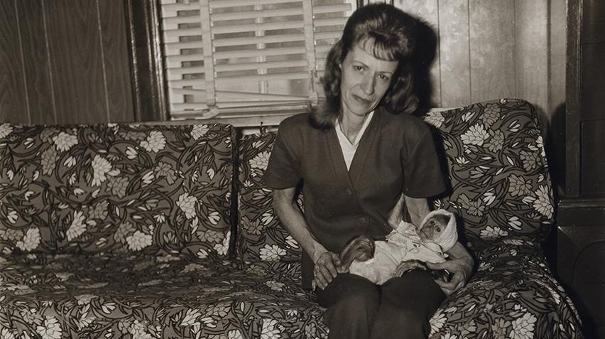 Black and white photograph of a woman holding a monkey that is swaddled like a baby