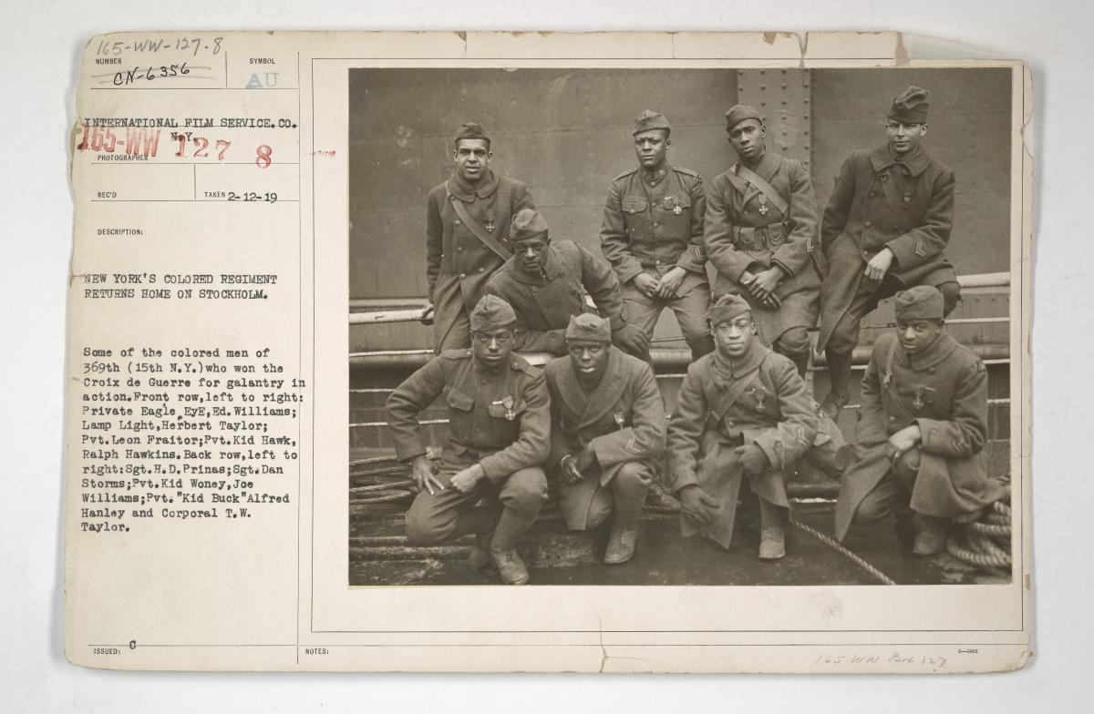  Photograph of nine uniformed members of the 369th infantry regiment posing aboard a ship