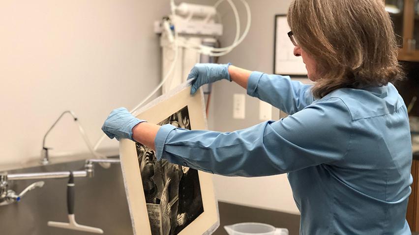 Conservator pulling a print from the sink of water