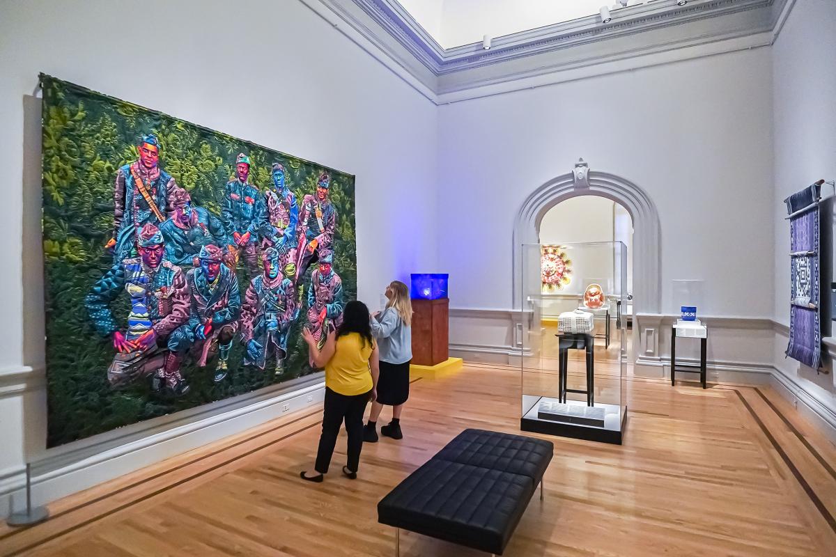 Two people look at large quilted portrait
