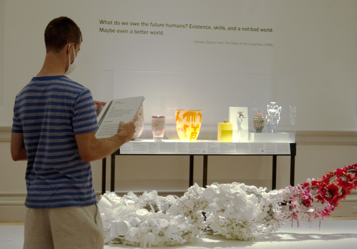 A visitor stands in the gallery, reading a binder of large print labels
