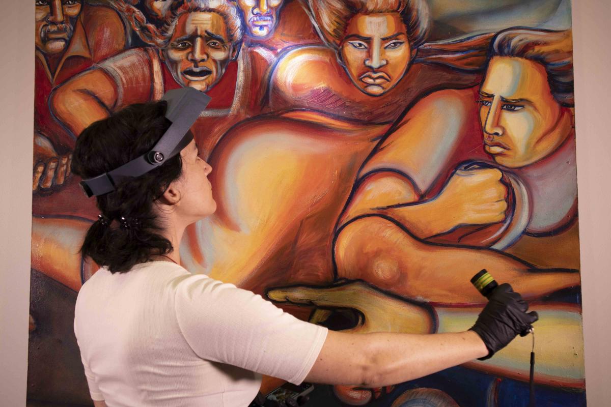 A conservator shines light on a mural 