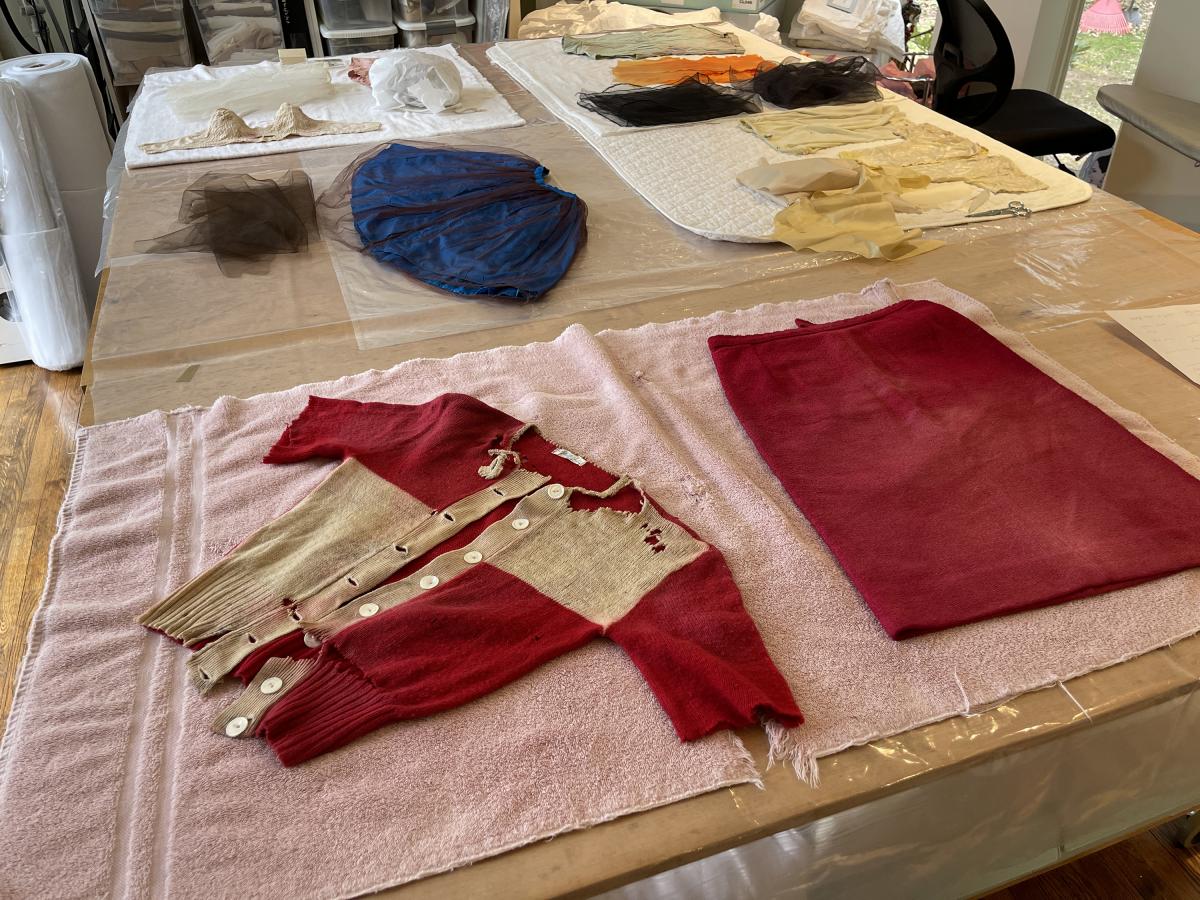 Red doll garments spread flat on a work table.