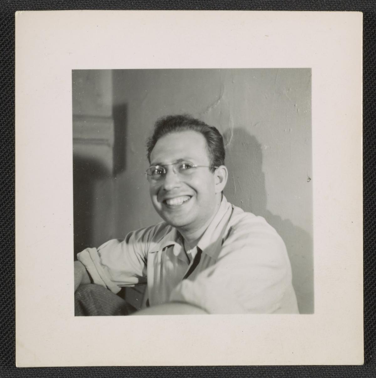 A black  and white photograph of the artist Philip Pearlstein. He is wearing glasses and has a big smile.