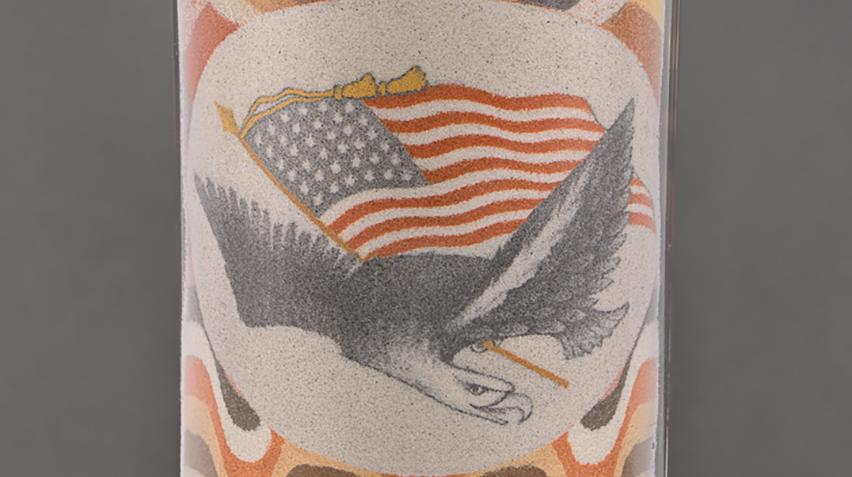 Detail of a sand bottle artwork showing an eagle carrying an American flag.
