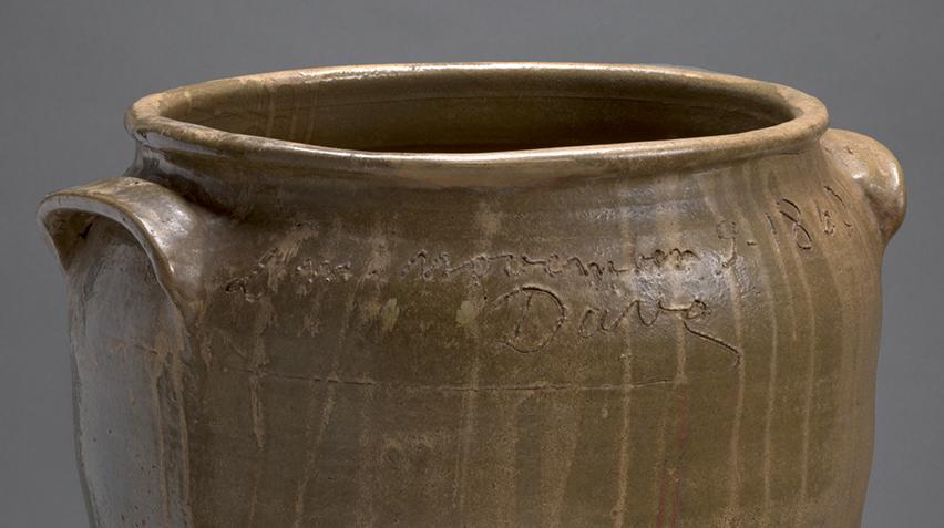 Detail of brown ceramic jar with writing and the signature "Dave" inscribed around the top.