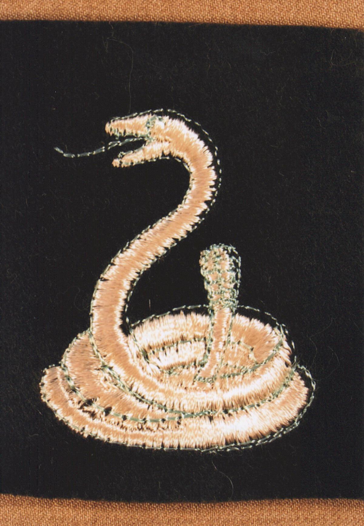 Embroidered patch showing a coiled snake with its tongue extended on a black background