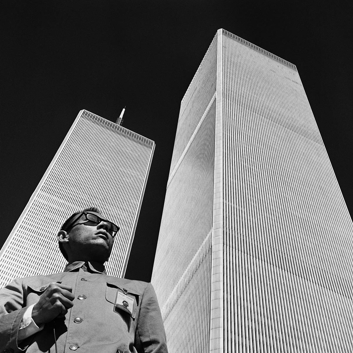 Photo of a man standing beside the Twin Towers in NYC