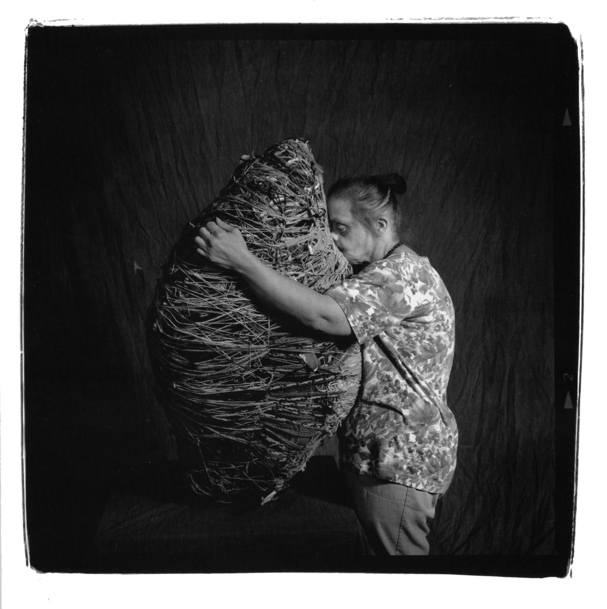 Judith Scott embracing one of her large sculptures