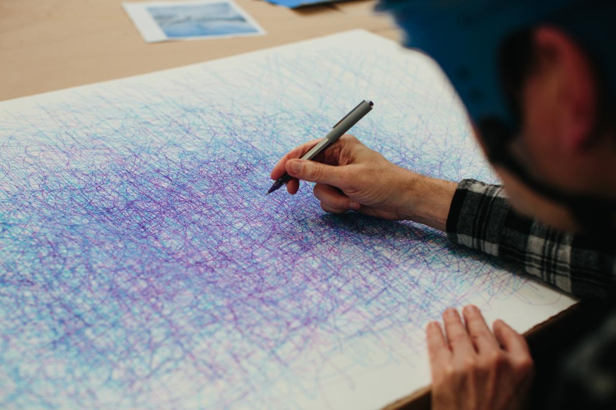 Artist Dan Miller draws lines on paper in different colored ink.