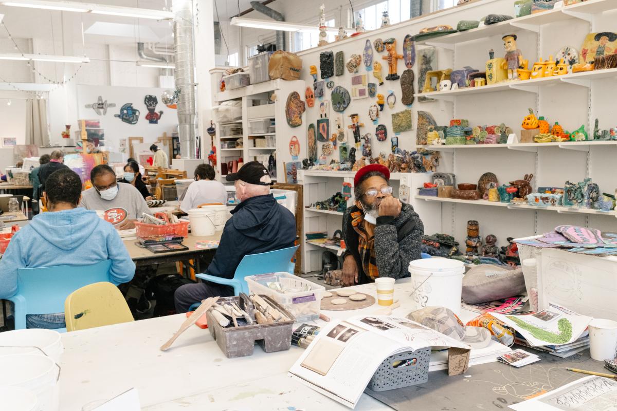 Artist Marion Bolton sitting in the studio surrounded by artworks