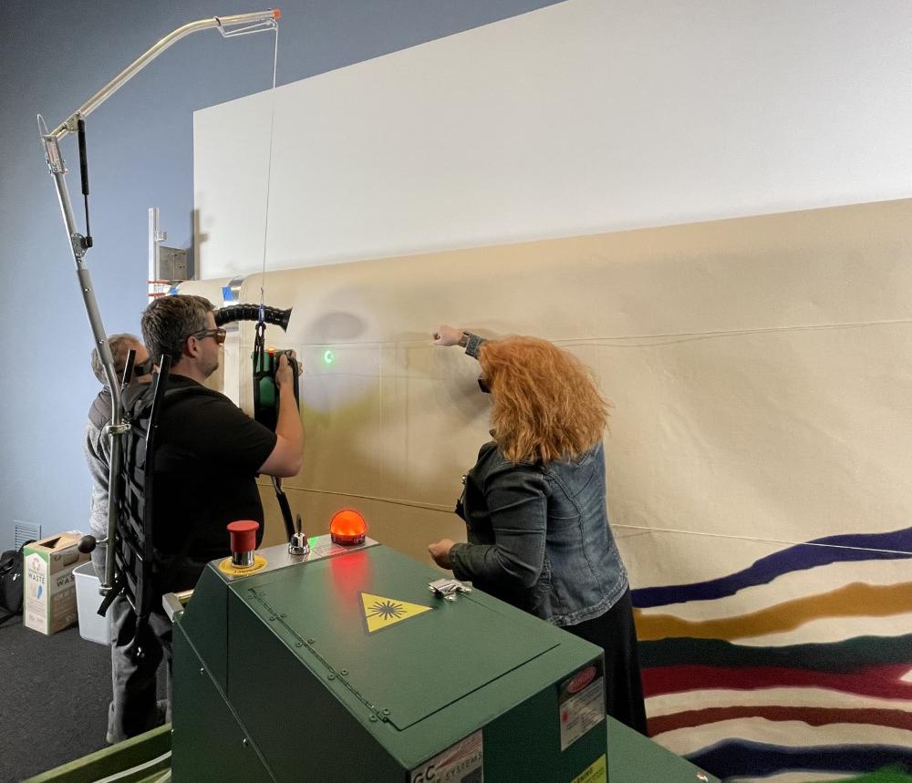 Photograph of two conservators working on a canvas.
