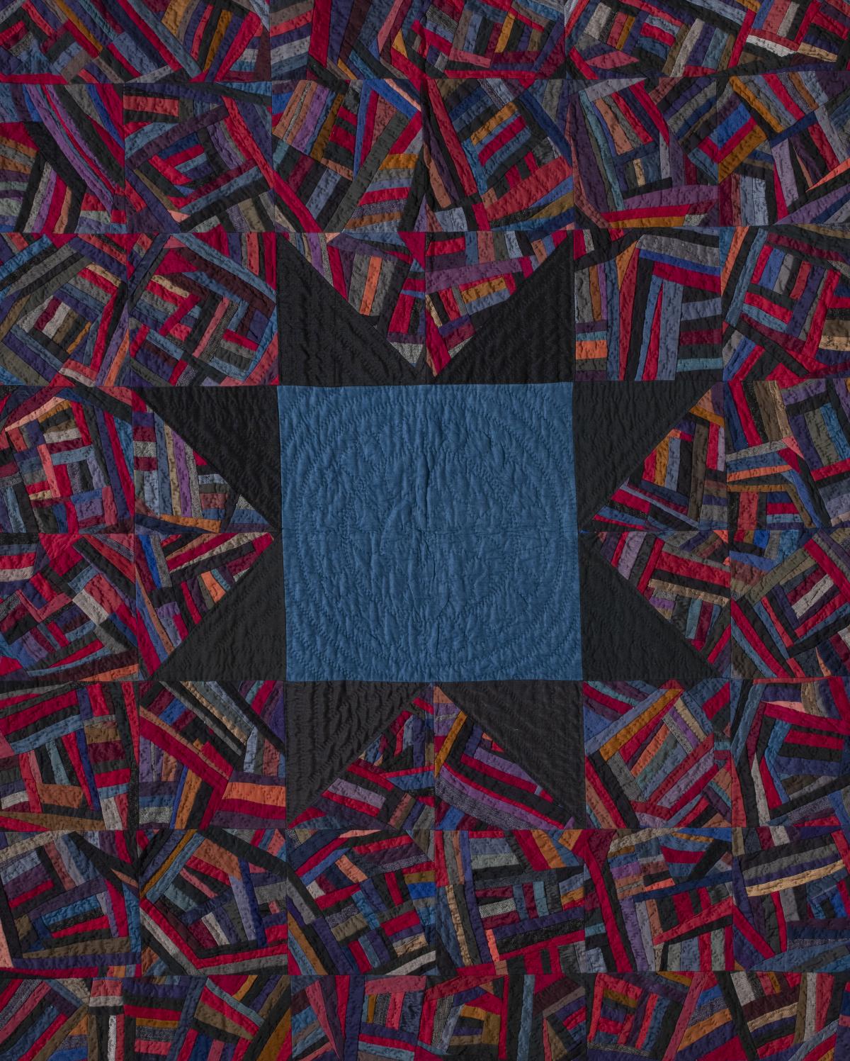 Quilt with a colorful, abstract pattern. At the center is a dark blue square with a black star as its border.