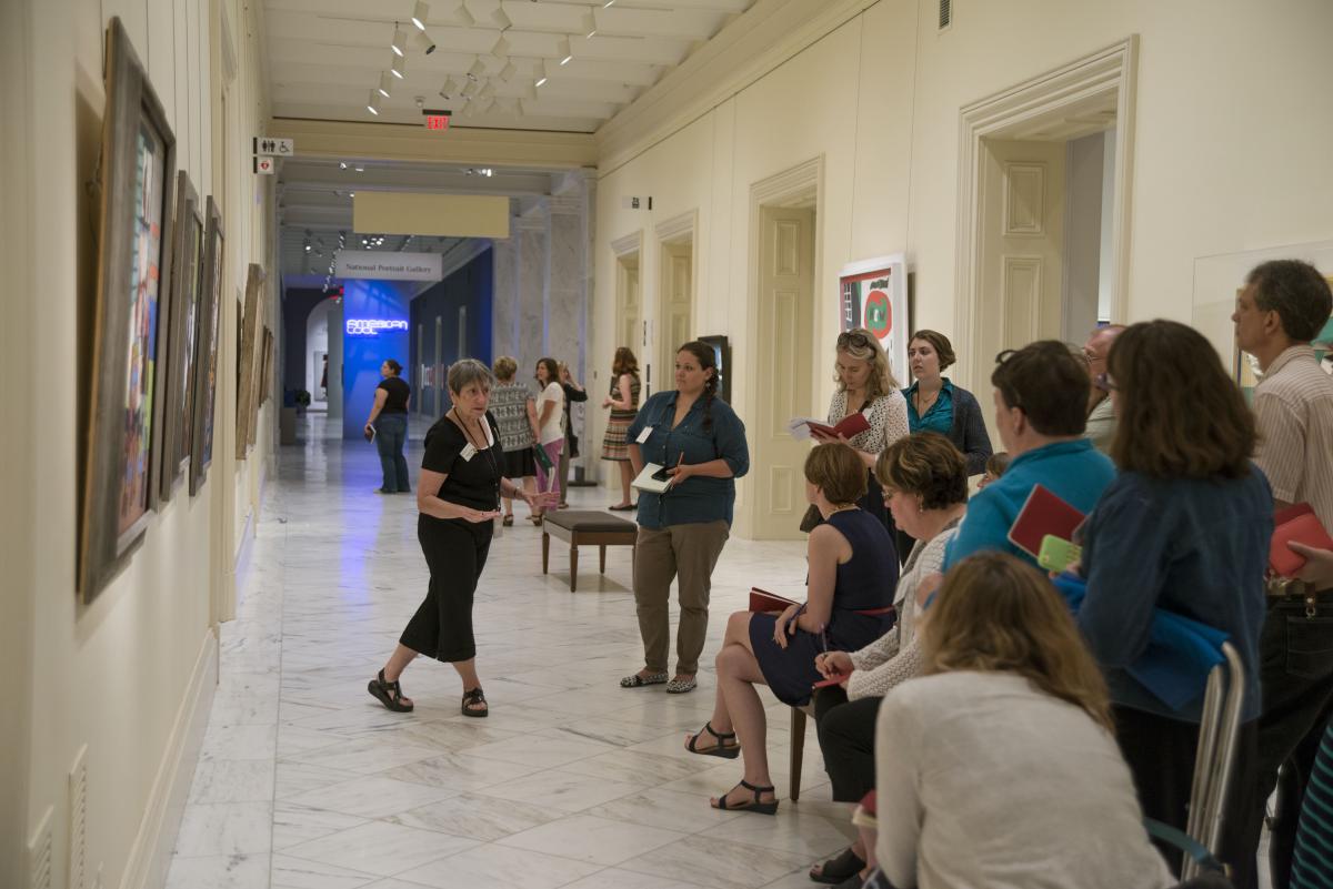 A docent talks about a painting to a large assembled group