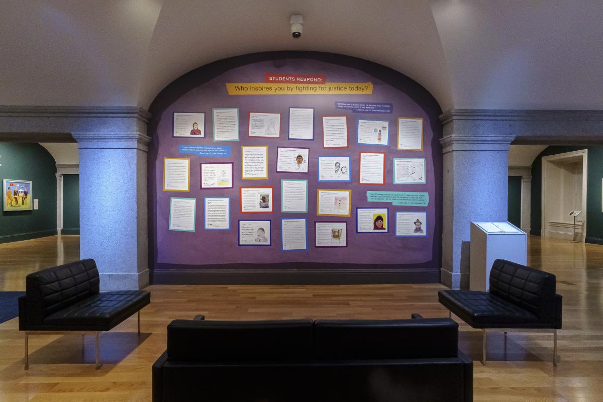Response cards with letters and drawings hang on a purple gallery wall.