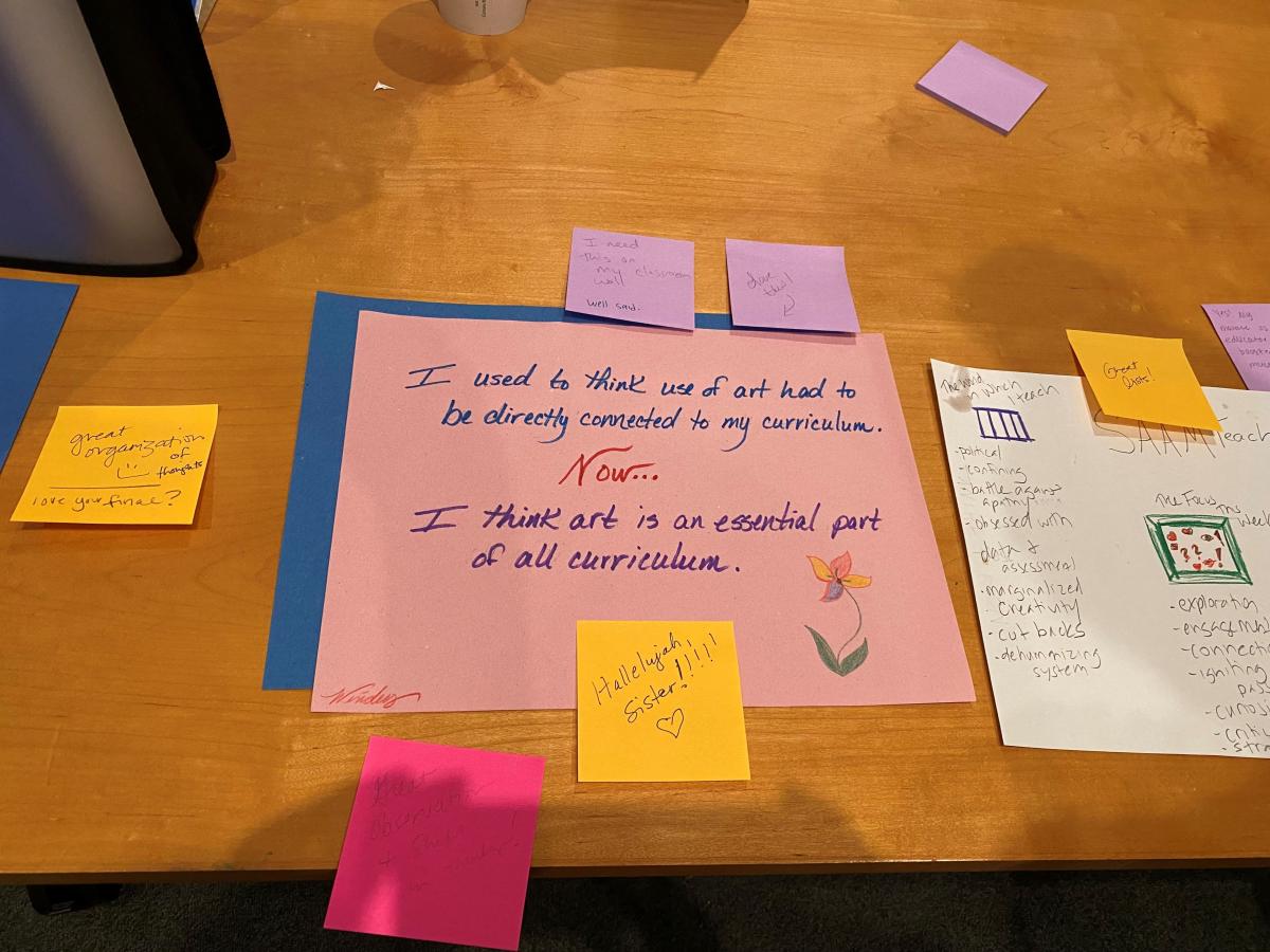 A table with colorful papers and written messages from a teacher that includes "I think art is an essential part of all curriculum"