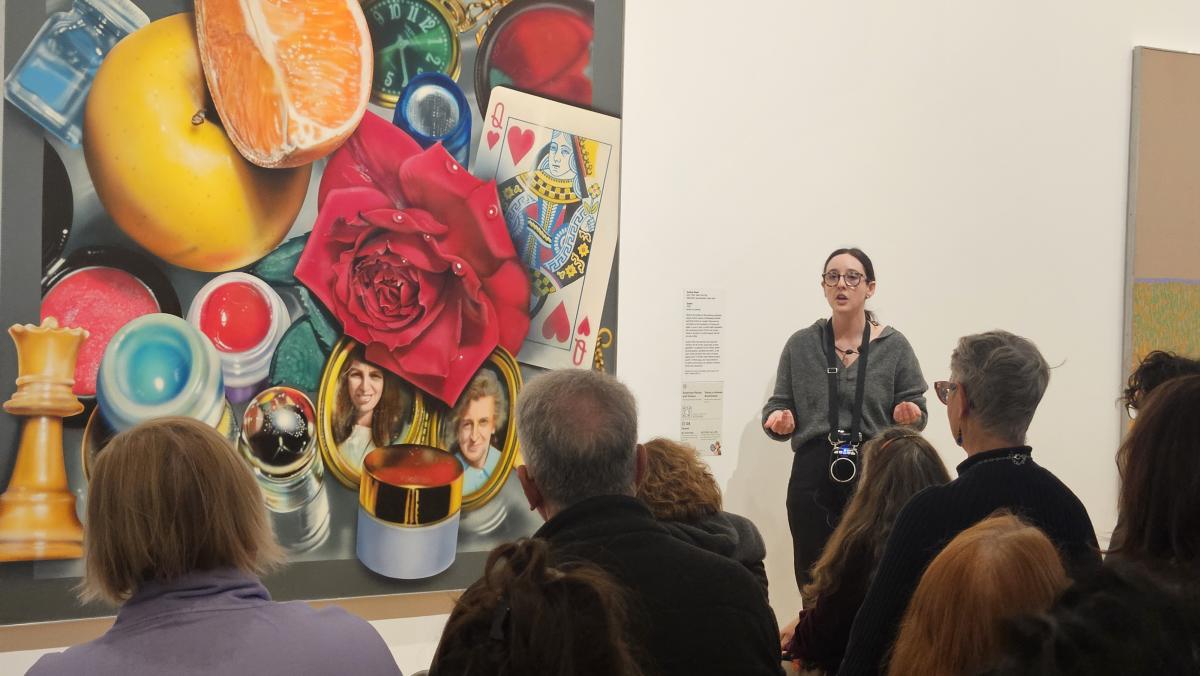 educator standing in front of audience describing painting next to her 