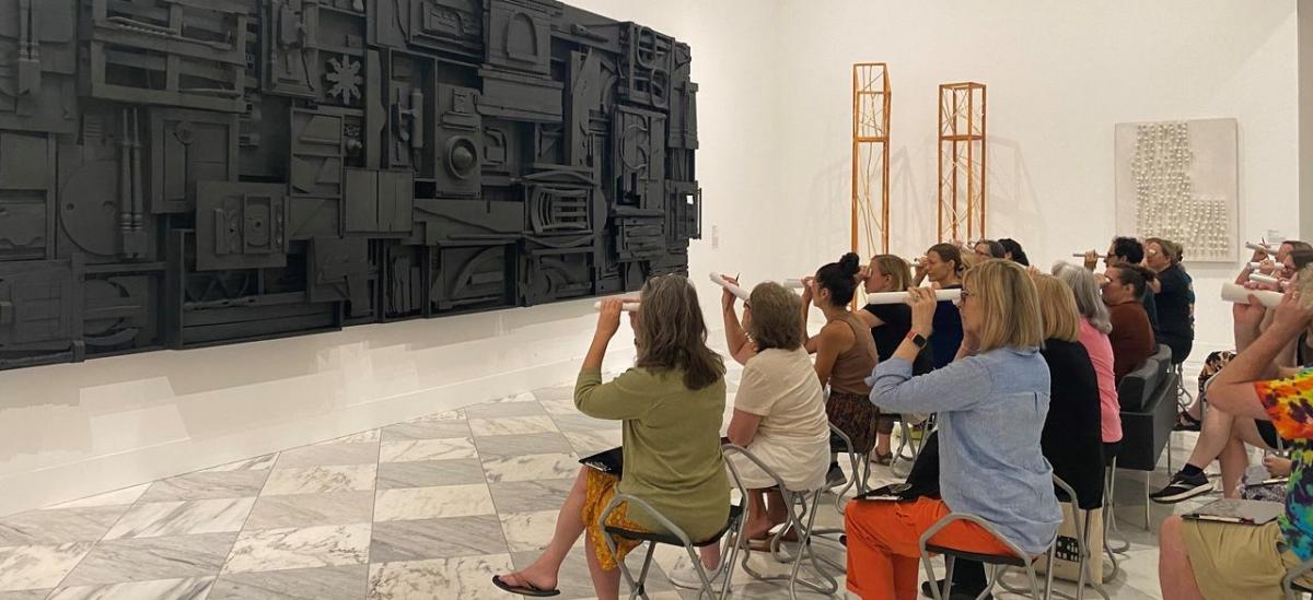 Photo of people sitting viewing artwork.