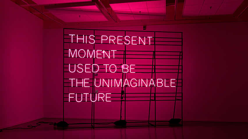 Blog - Contemporary Craft in Focus, This Present Moment, homepage crop A pink neon sign that reads "This Present Moment Used to be the Unimaginable Future."