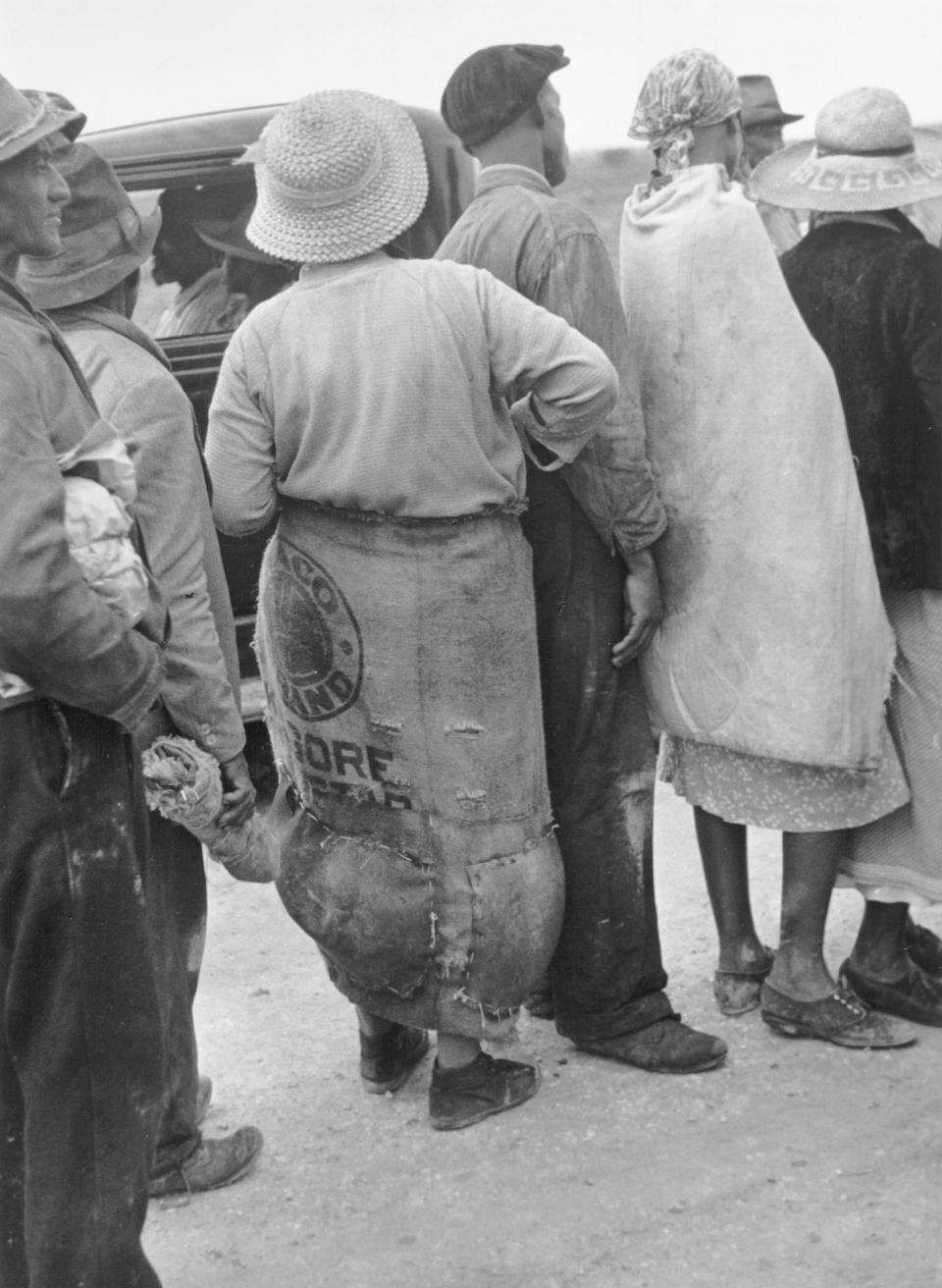 Migrant agricultural workers waiting in line behind truck in the field ...