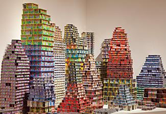 An installation of scratch & win lottery tickets stacked on top of one another forming structures. 