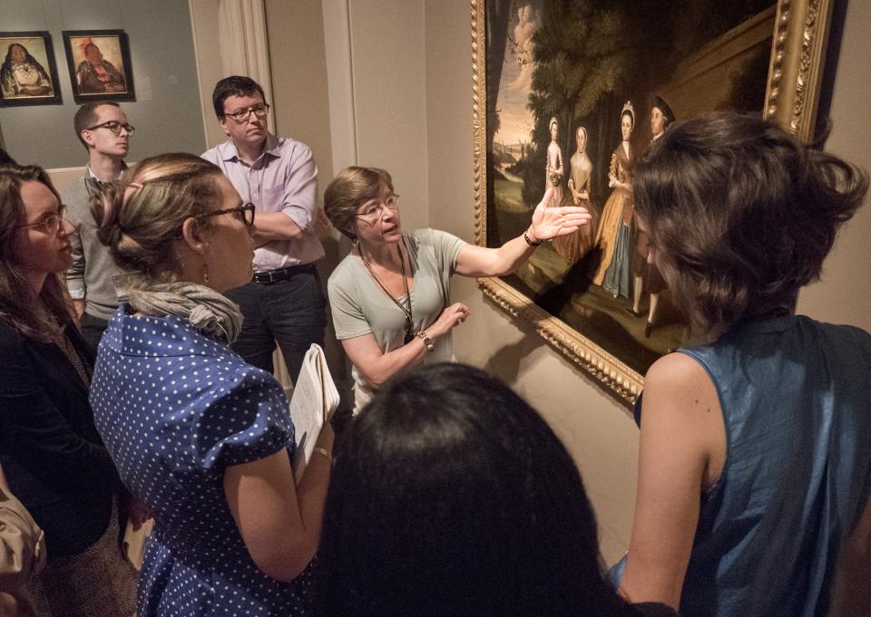 This is a picture of Eleanor Harvey giving a talk in front of a painting at the Smithsonian American Art Museum.
