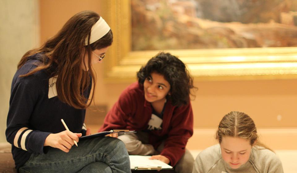 A photograph of three children in a museum sitting and talking.