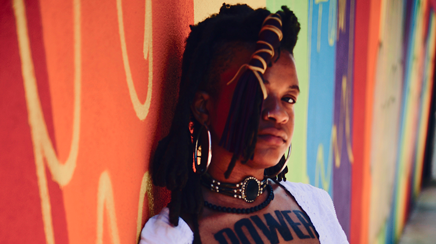 a woman with a tattoo that says "power" leaning against a wall