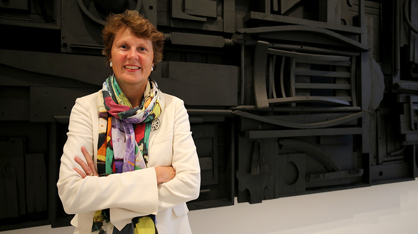 A woman stands in front of a black sculpture