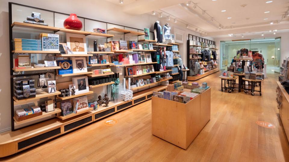 A museum store filled with bookshelves and tables of souvenirs 