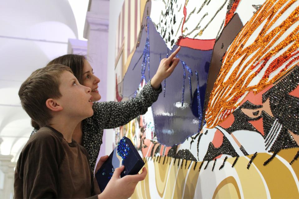 An educator points out the details of Mickalene Thomas's painting to a student