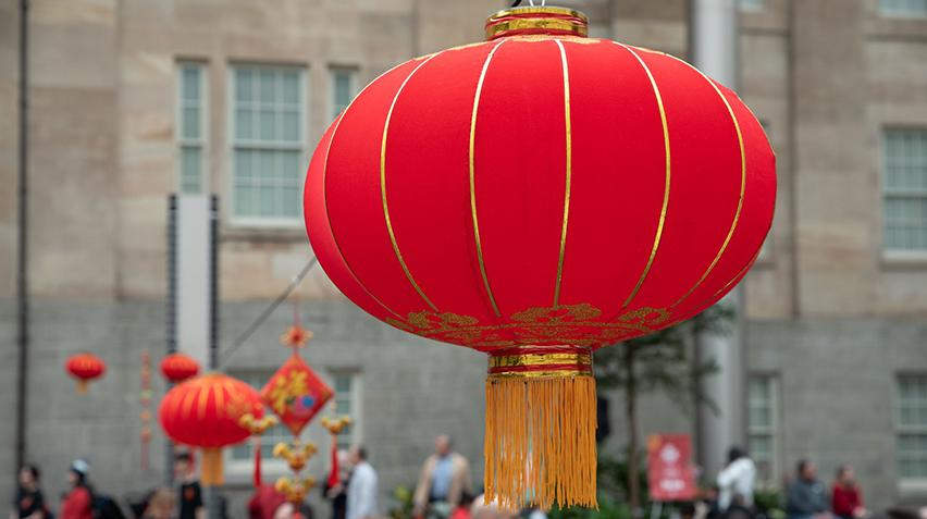 Large, red and gold lanterns hanging from a string outdoors